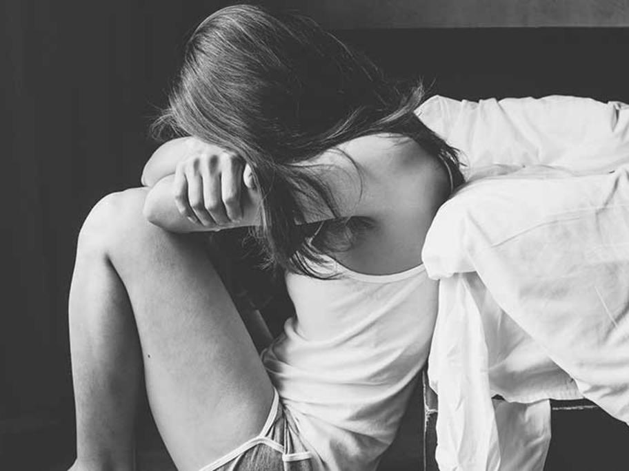 Woman crouched and holding head